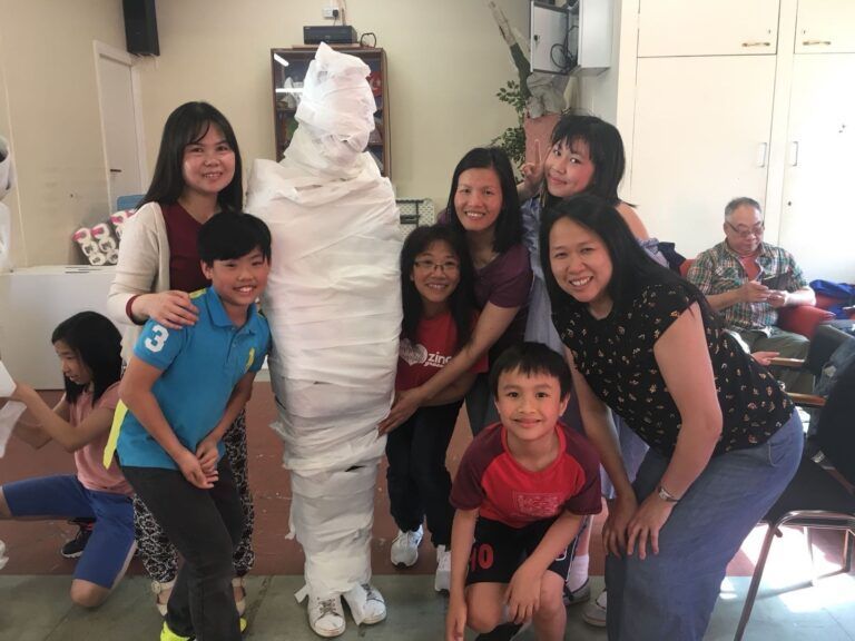 A group of people standing around a mummy wrapped in paper