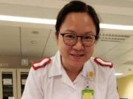 A nurse wearing glasses and a white uniform is smiling for the camera.