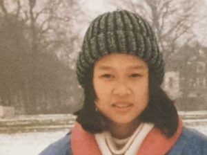 A young girl wearing a knitted hat and jacket stands in the snow
