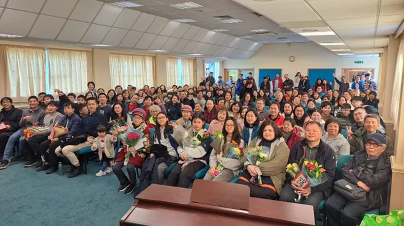 一大群人正在房間裡擺姿勢拍照。