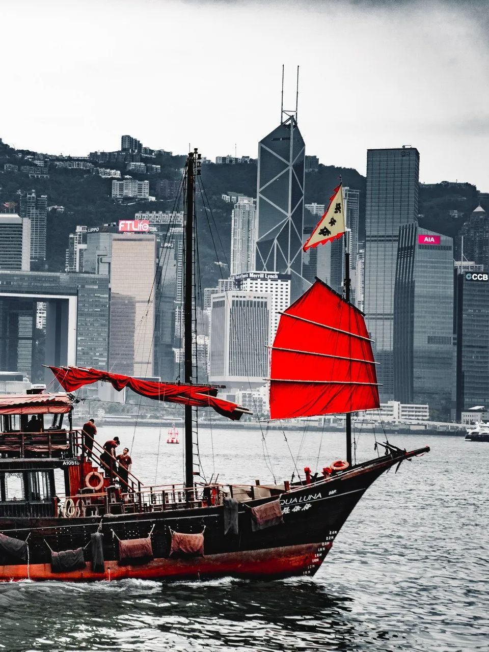 A boat with a red sail is floating in the water