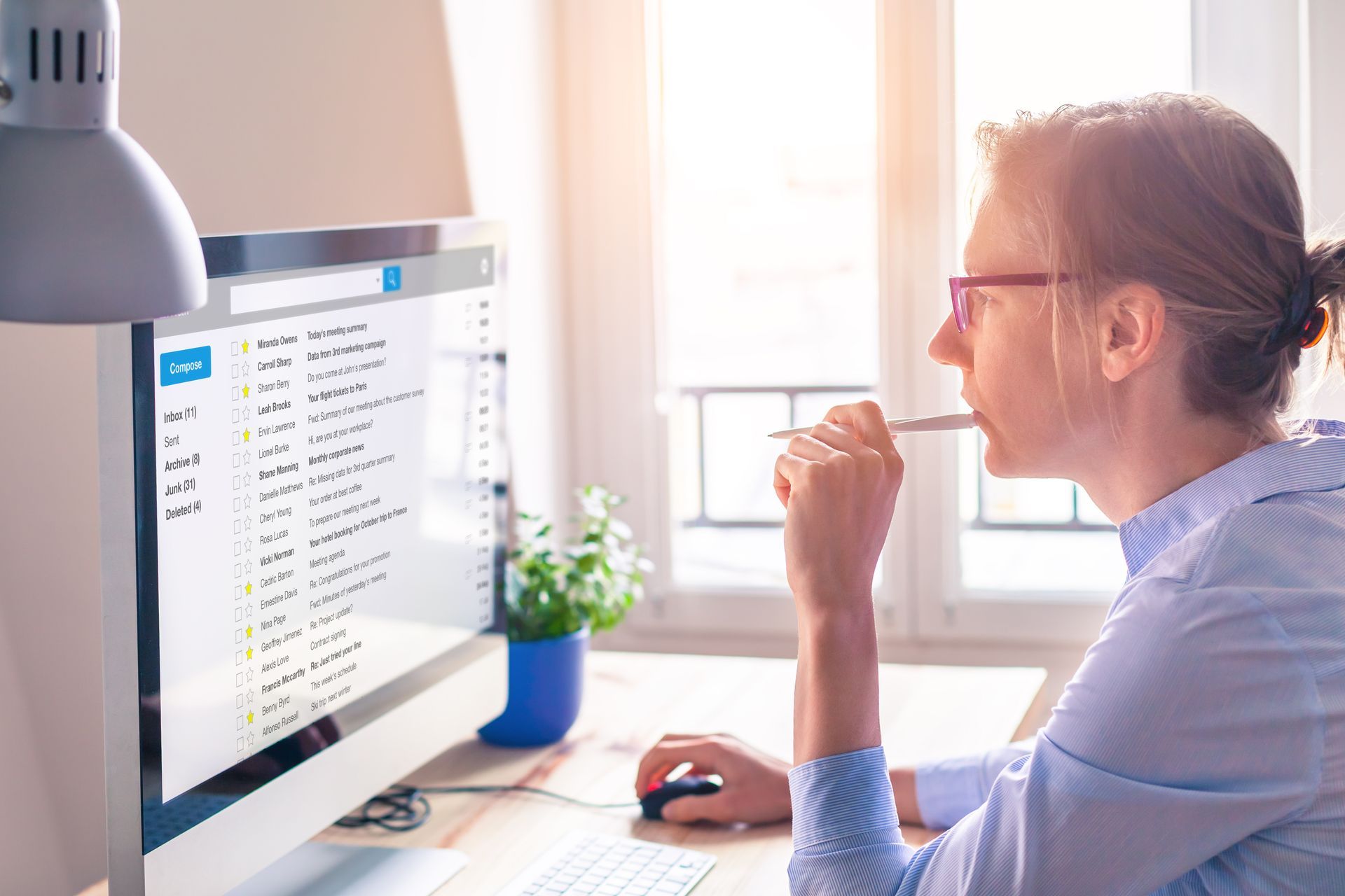 Female business person reading email on computer screen at work.