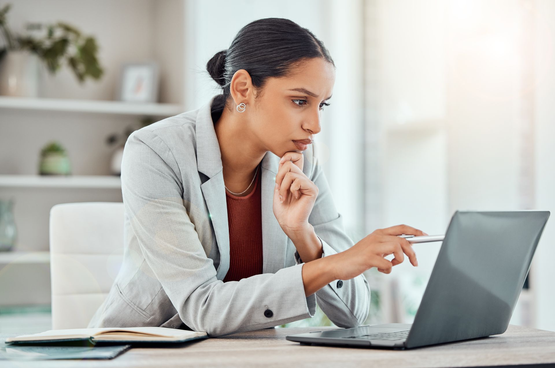 A woman is sitting at a desk using a laptop computer.