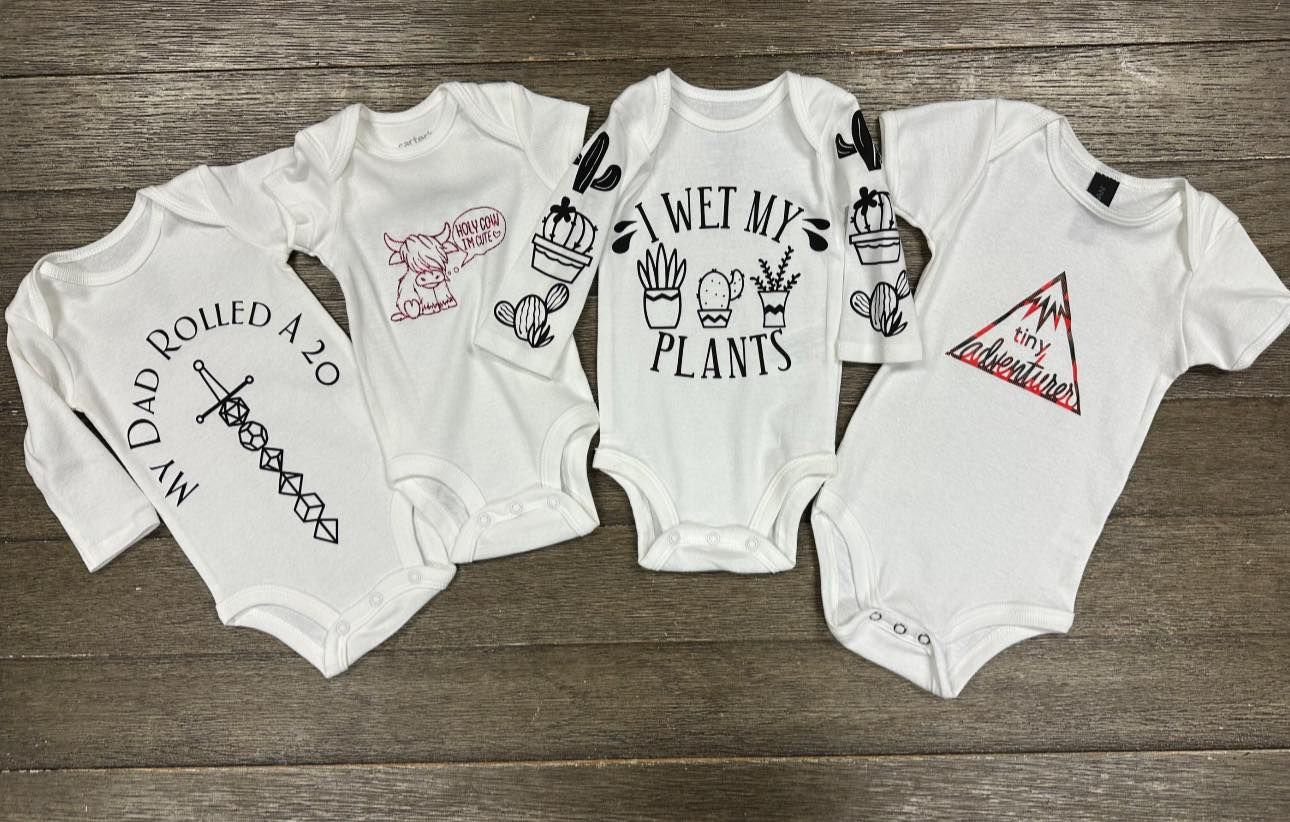A group of baby onesie 's sitting on top of a wooden table.
