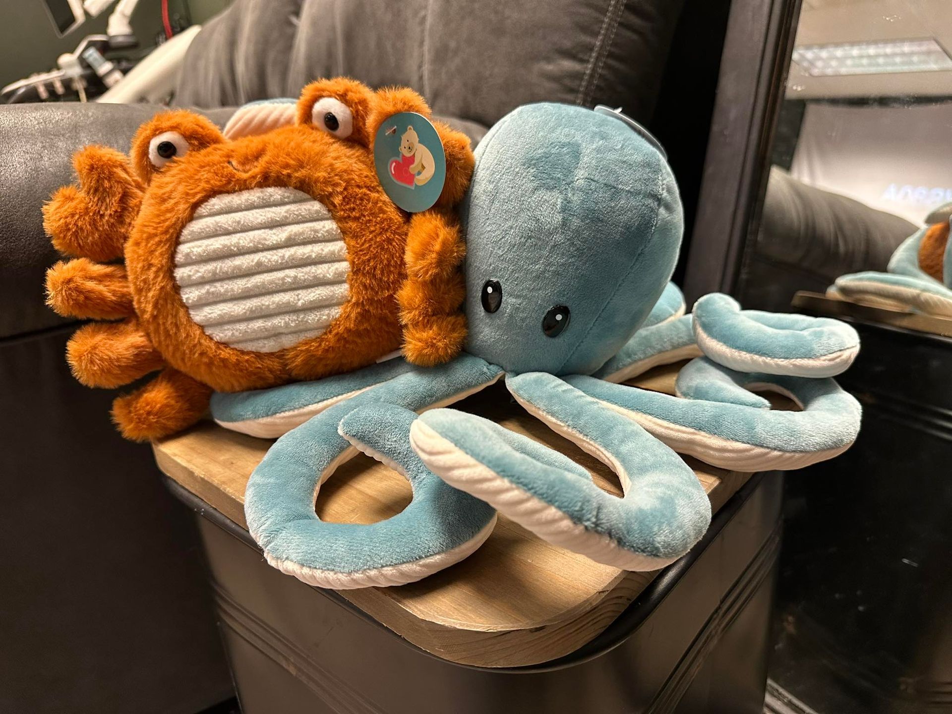 A stuffed octopus and a stuffed crab are sitting on a couch.
