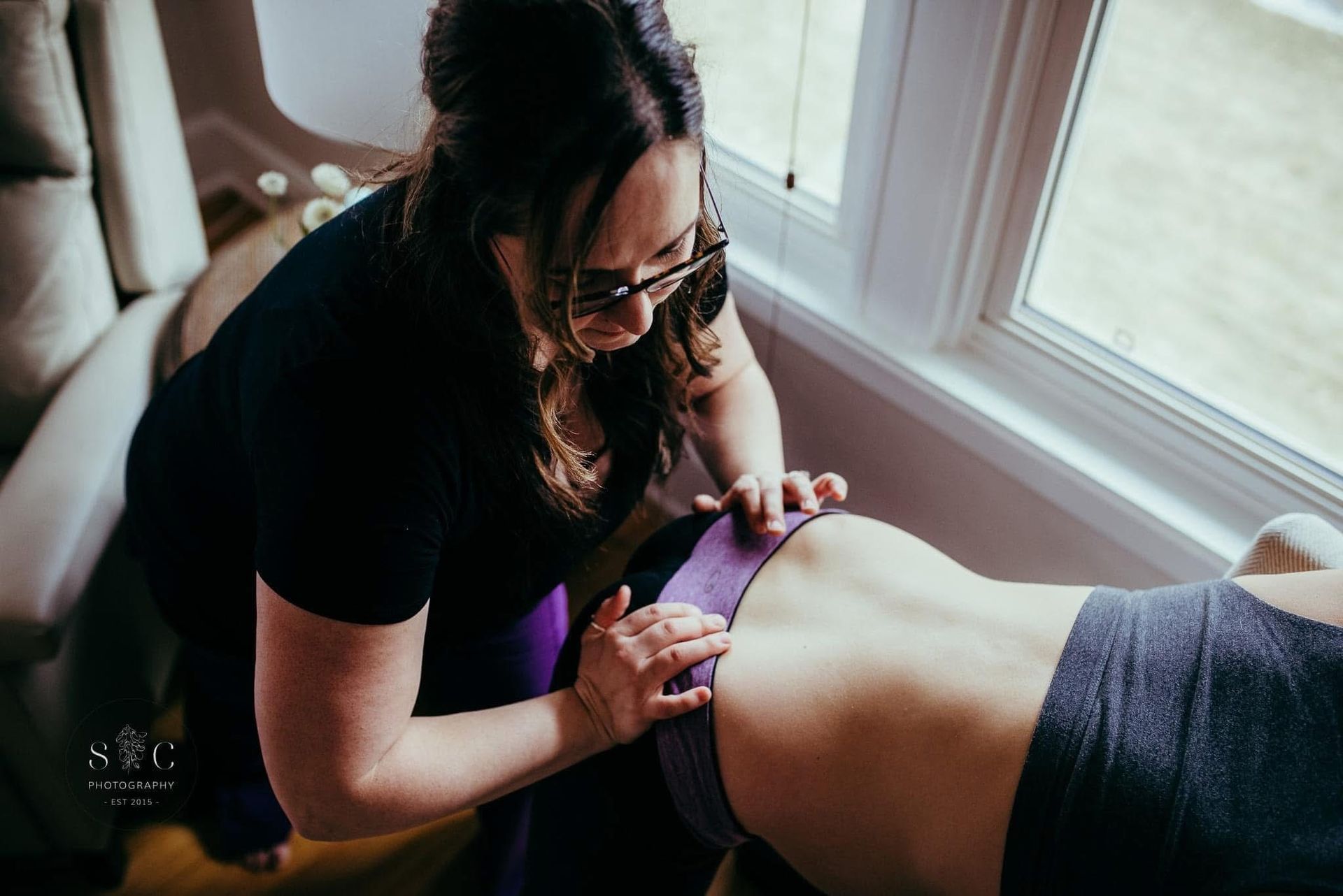 A woman is giving a massage to a woman on a table.