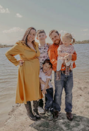 A family is posing for a picture on the beach.