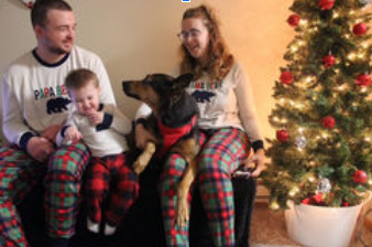 A family is posing for a picture in front of a christmas tree.
