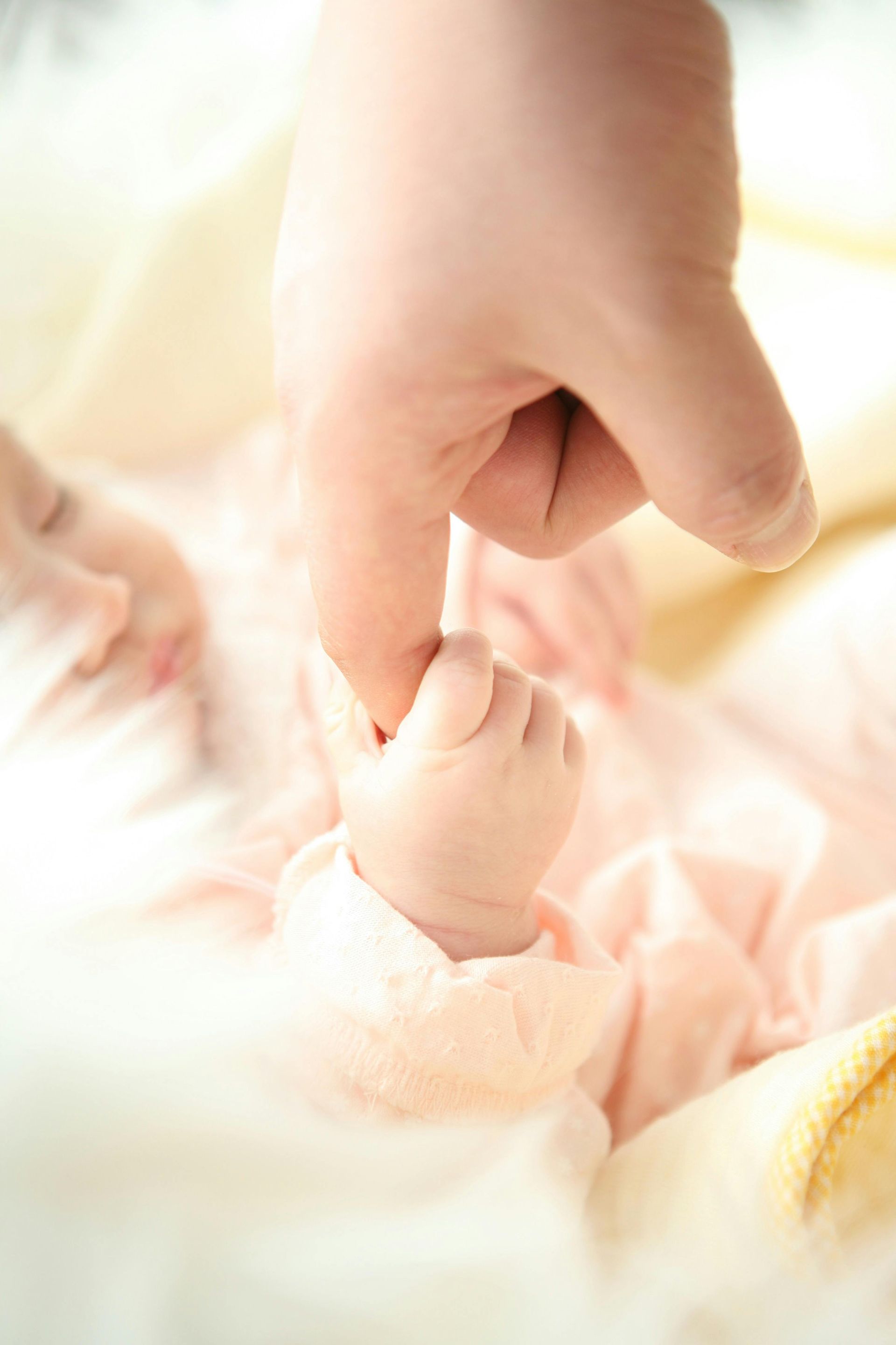 A close up of a person holding a baby 's hand.