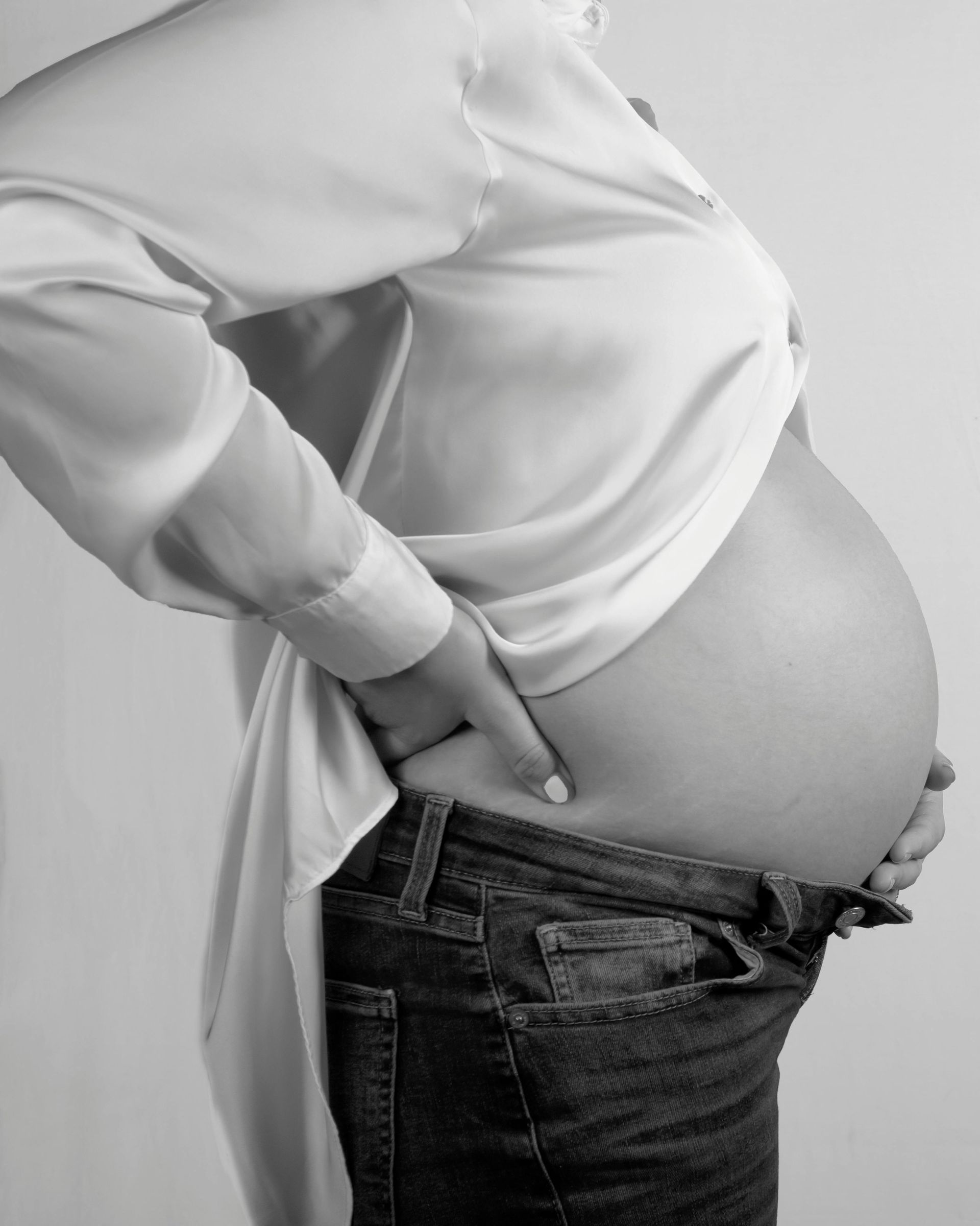 A black and white photo of a pregnant woman holding her belly