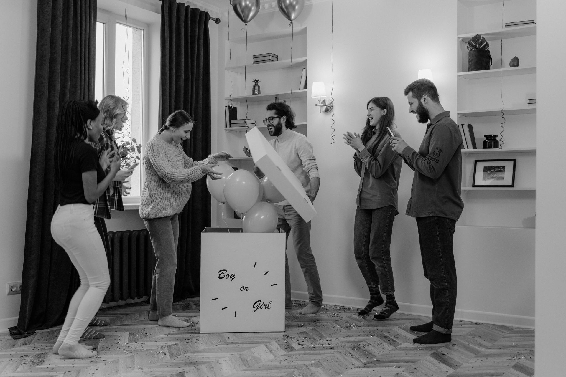 A group of people are standing around a box with balloons in it.