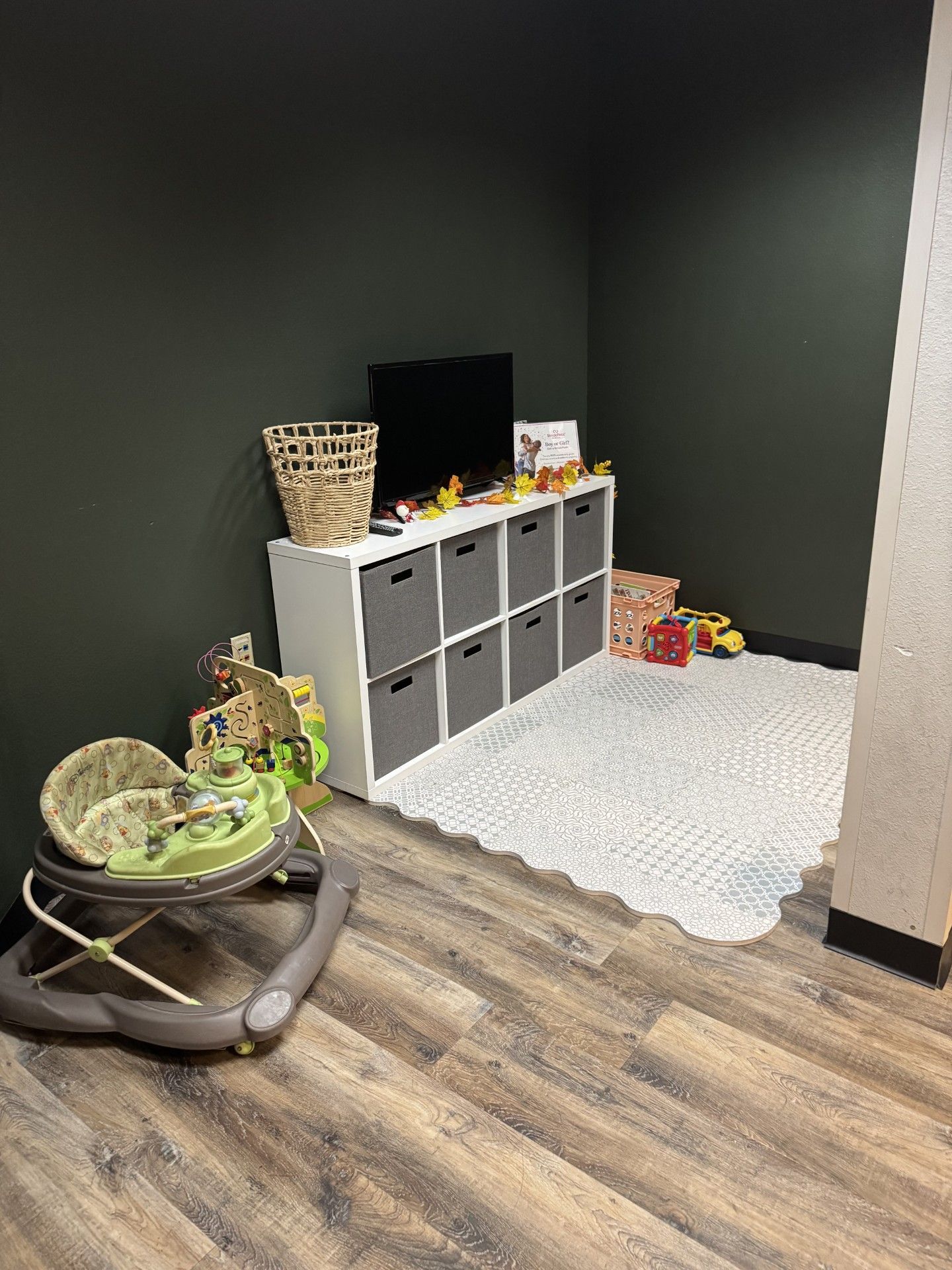A baby walker is sitting in a room next to a television.