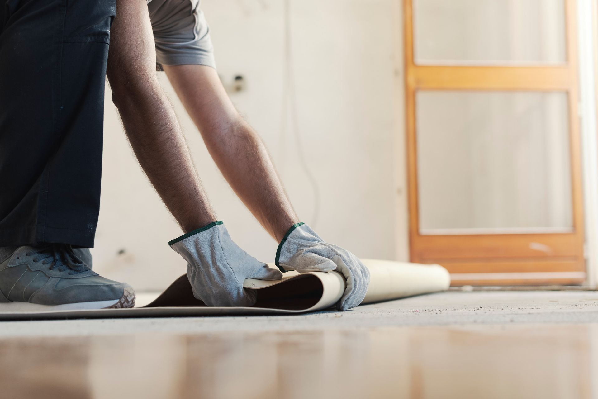 A man is rolling a piece of carpet on the floor.