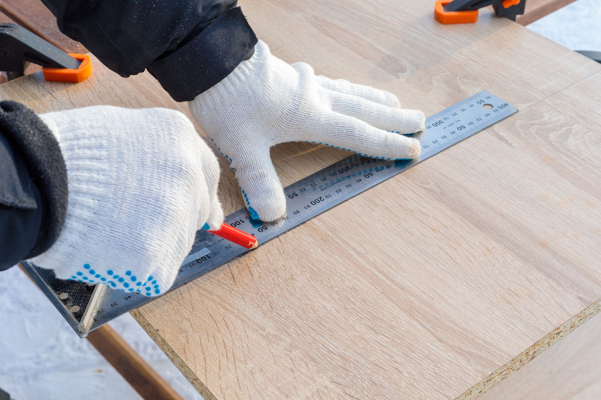 A person is measuring a piece of wood with a ruler.