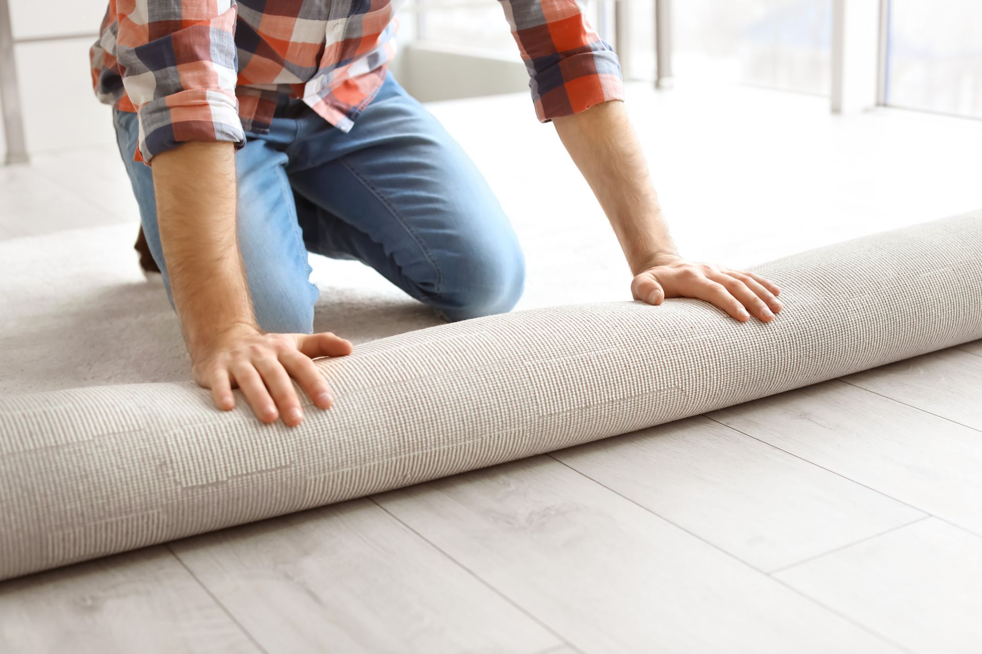 A person is rolling a rug on a wooden floor.
