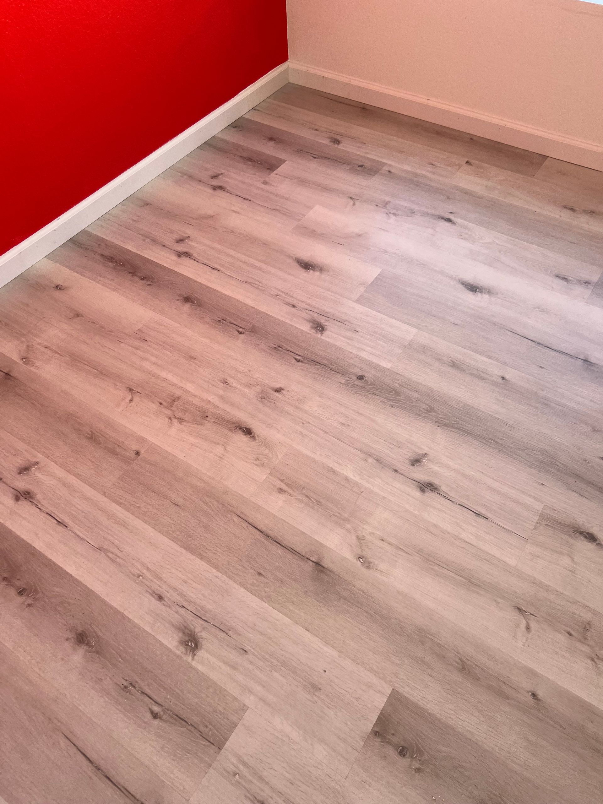 A room with a wooden floor and red color on the wall.