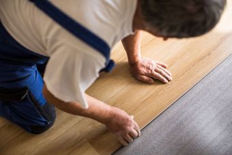 A man is installing a wooden floor in a room.
