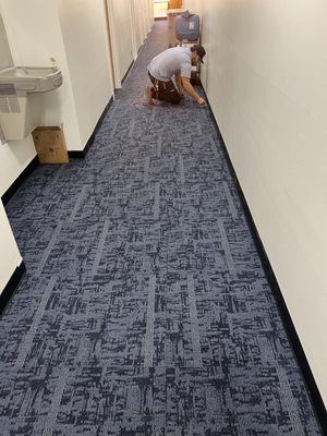 A man is kneeling down on the floor of a hallway.
