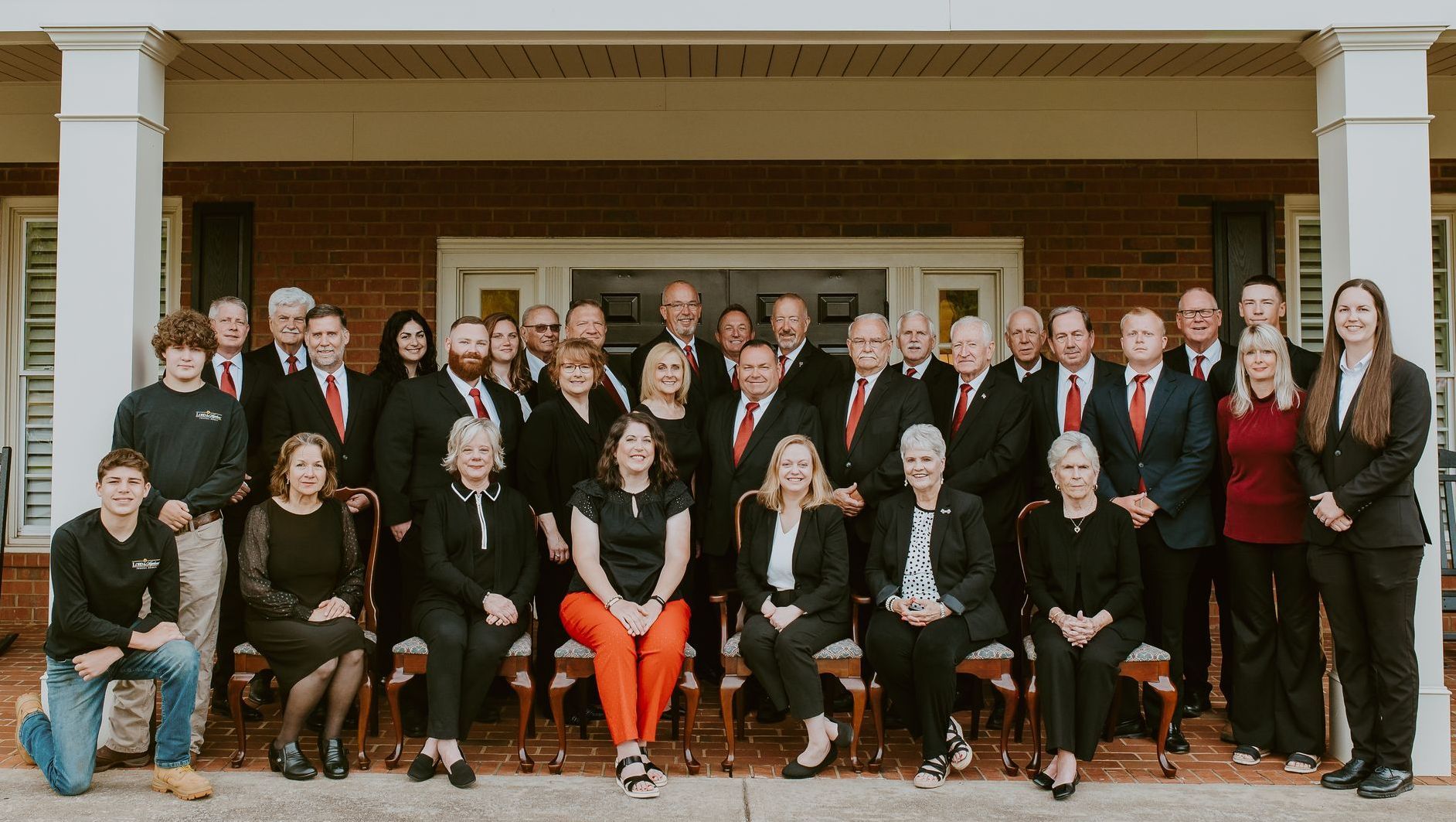 a large group of people are posing for a picture in front of a building .