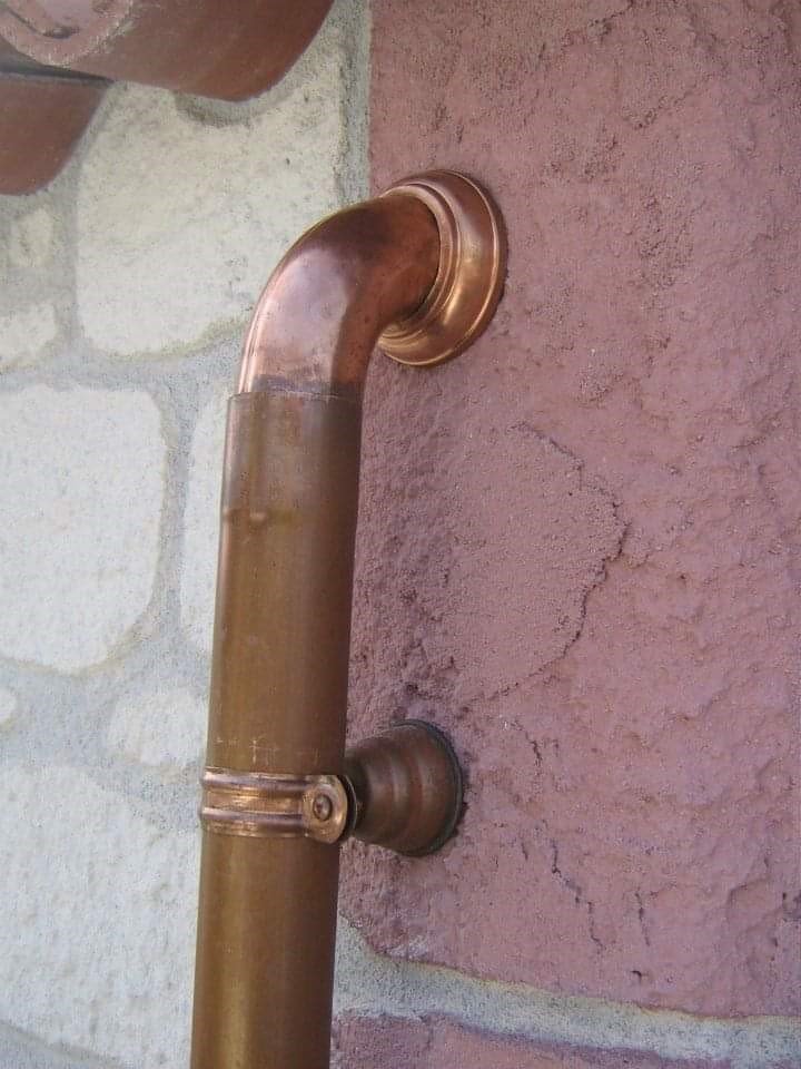 Un tubo di rame è attaccato a un muro di mattoni