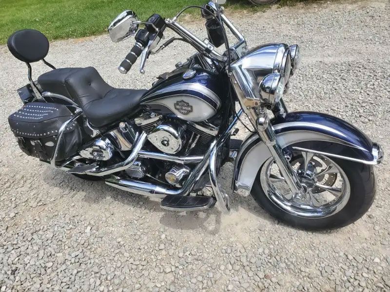 Chrome and blue Harley-Davidson motorcycle with saddlebags parked on gravel.