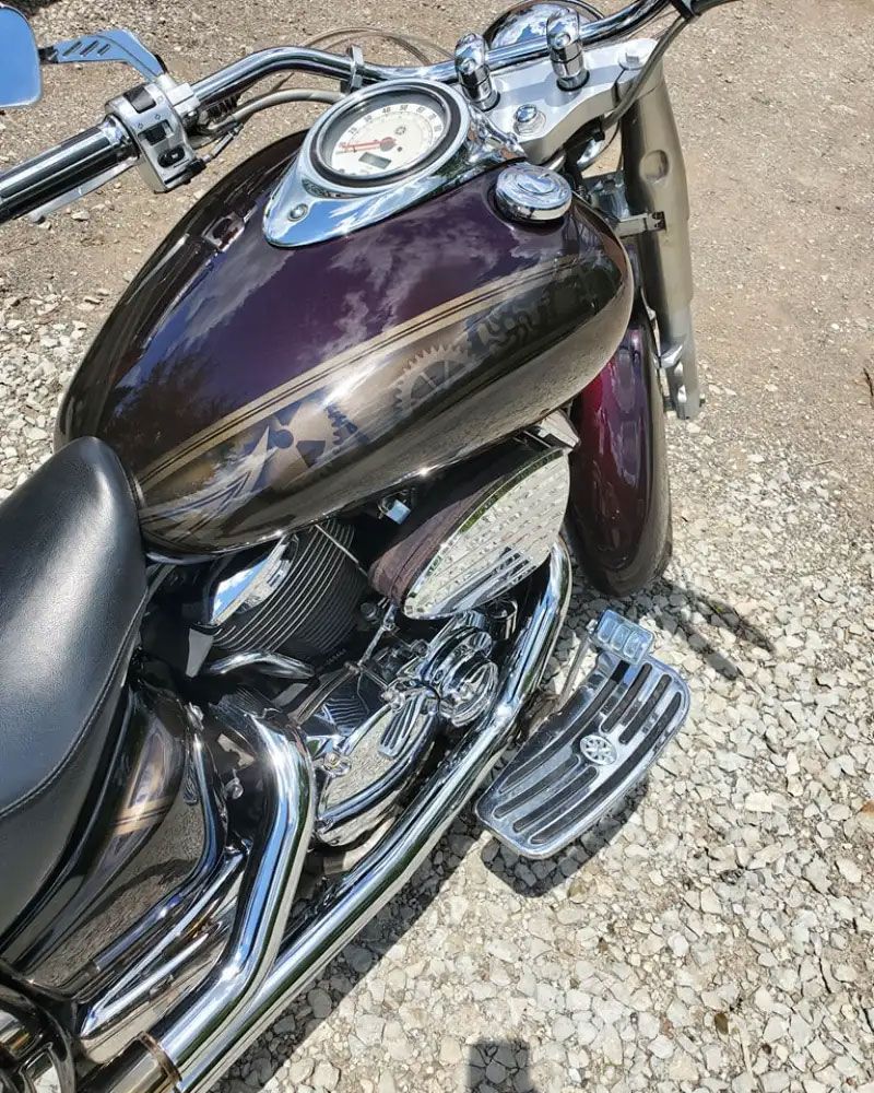 Purple and chrome motorcycle parked on gravel.