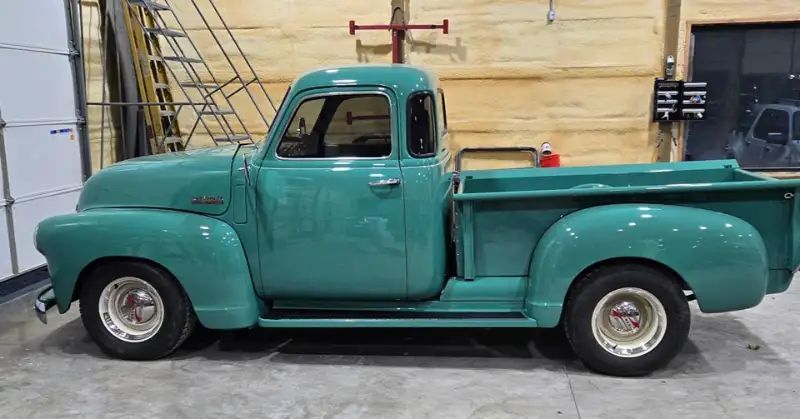 Teal vintage Chevrolet pickup truck parked in a garage.