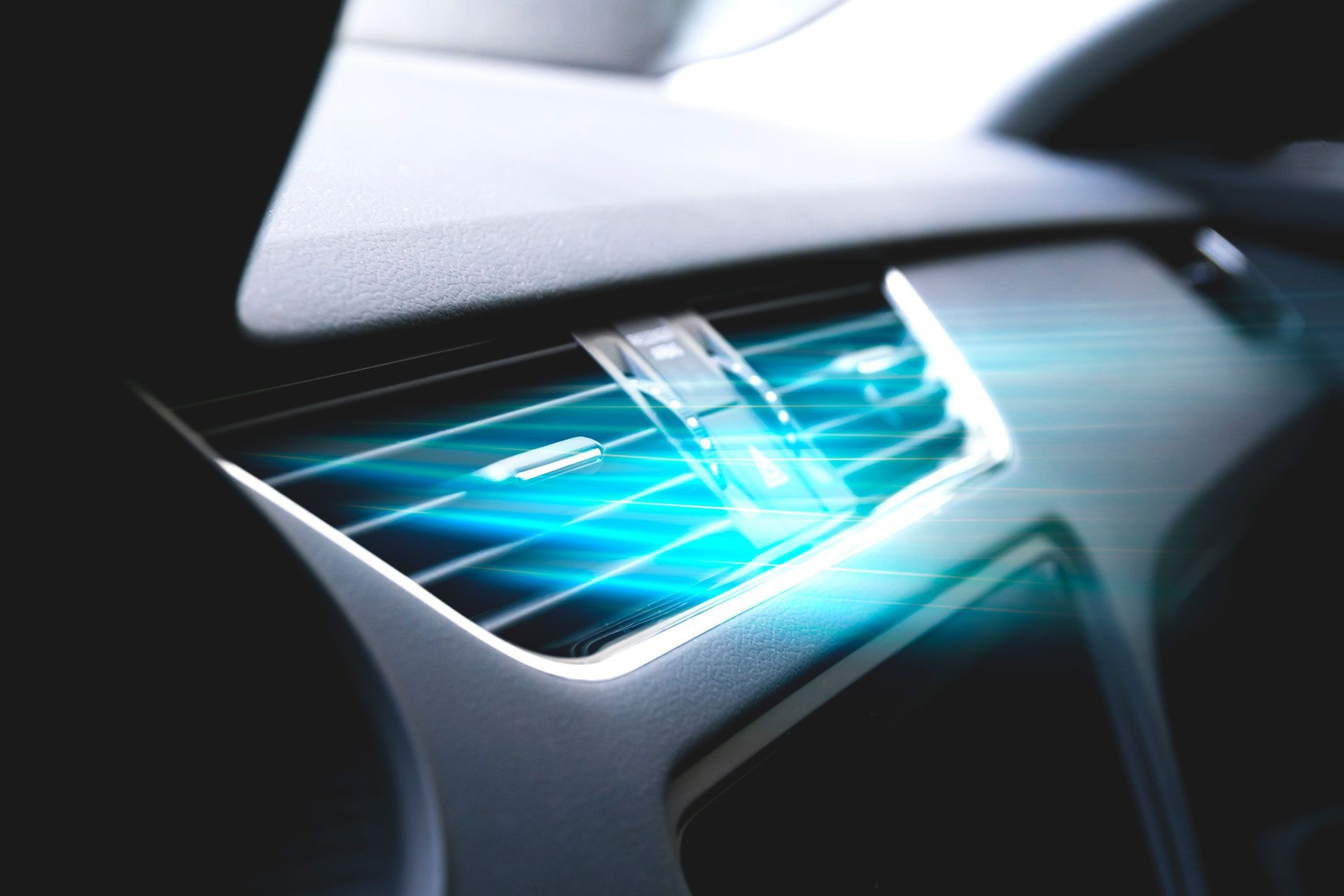 Car dashboard air vent with blue light emitting from it.