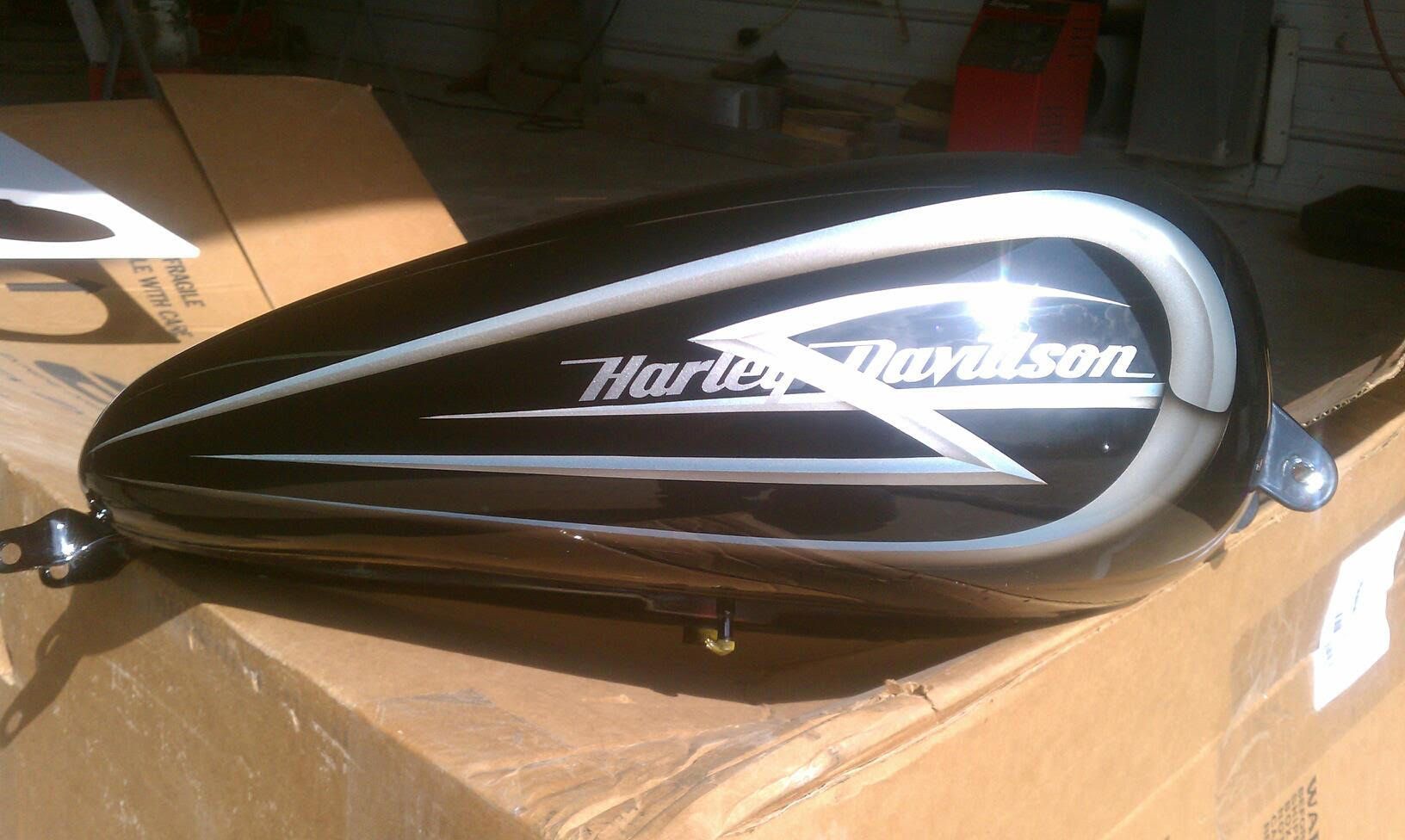 Black Harley-Davidson motorcycle gas tank with silver accents and logo on a cardboard box.
