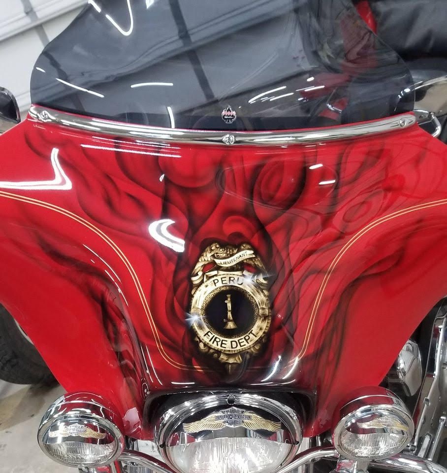 Red motorcycle fairing with a firefighter's badge and flames.