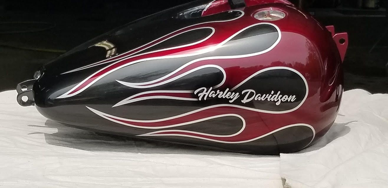 A black and red Harley Davidson motorcycle gas tank with flame design.