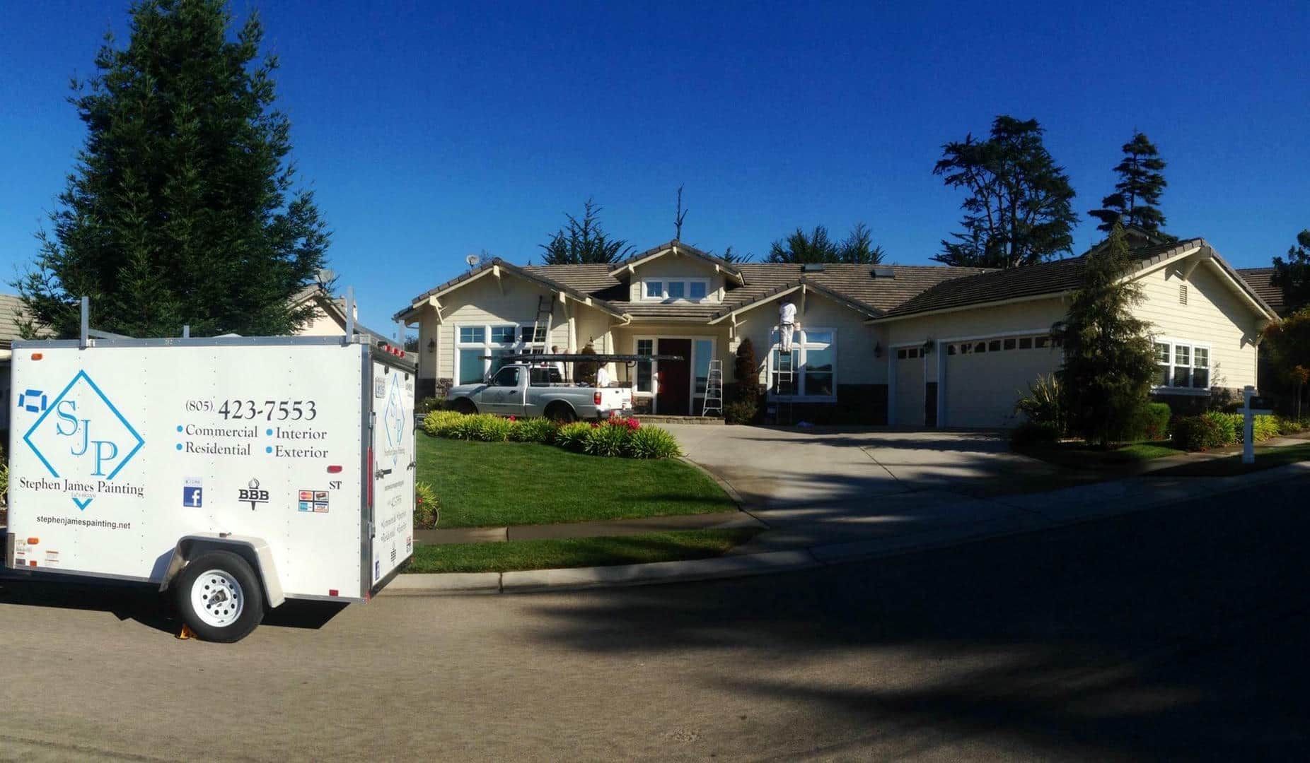 A white trailer is parked in front of a house.