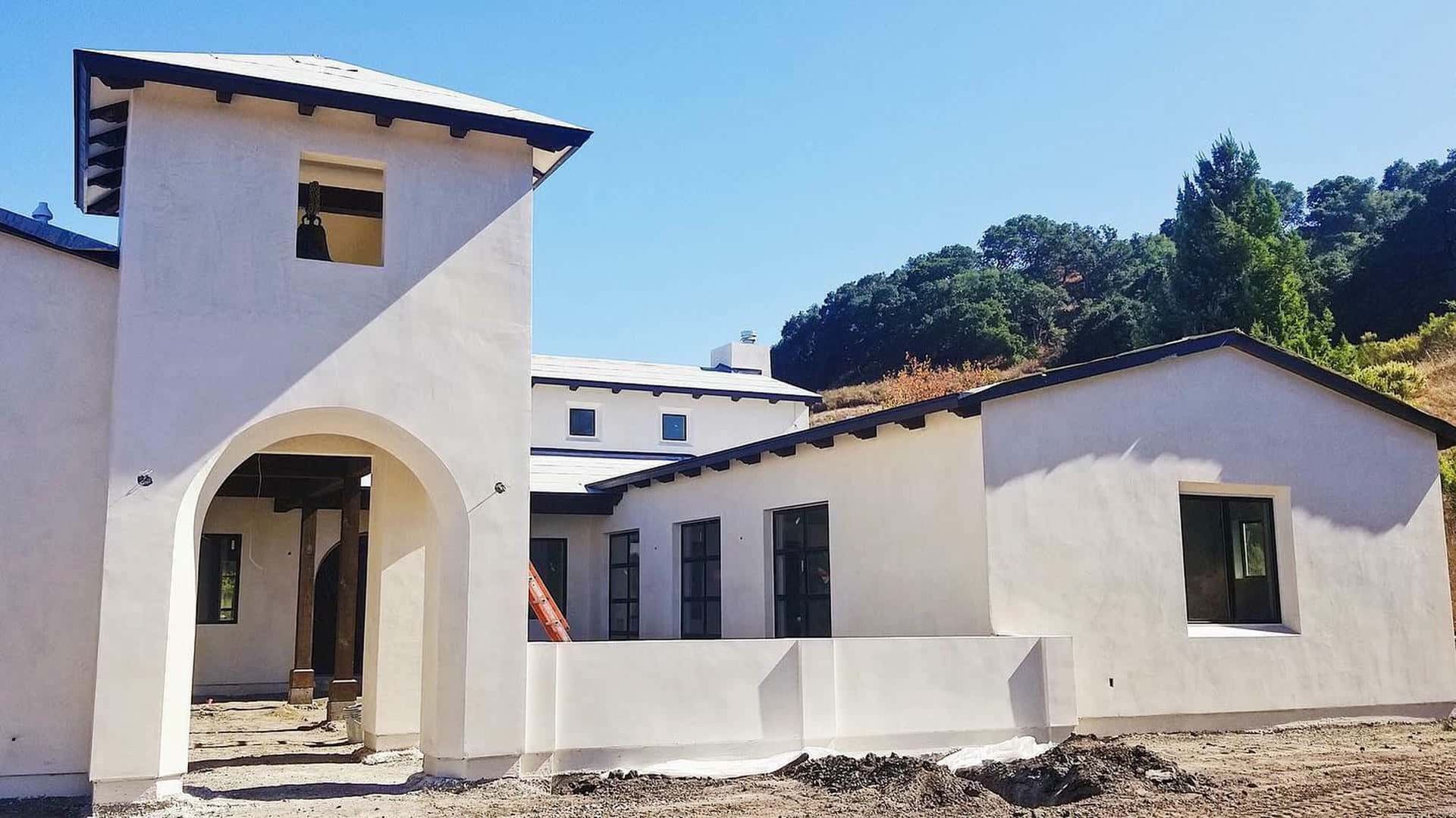 A white house with a black roof is under construction