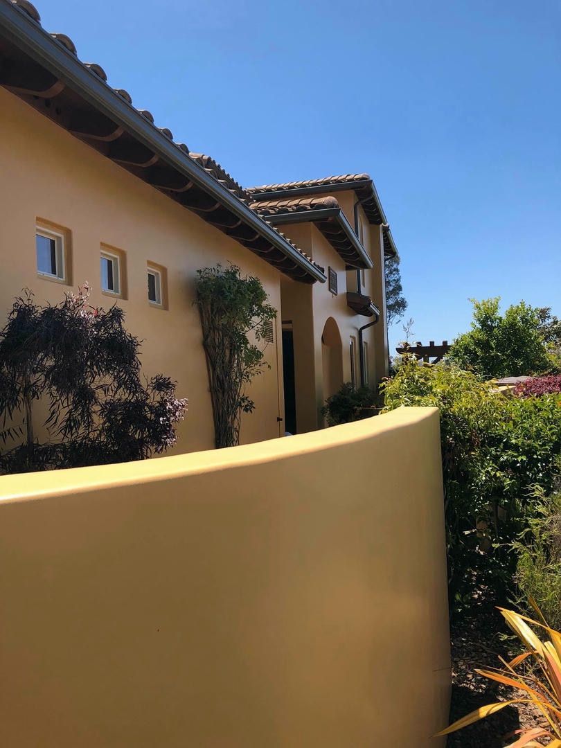 A large house with a yellow wall and a blue sky in the background.