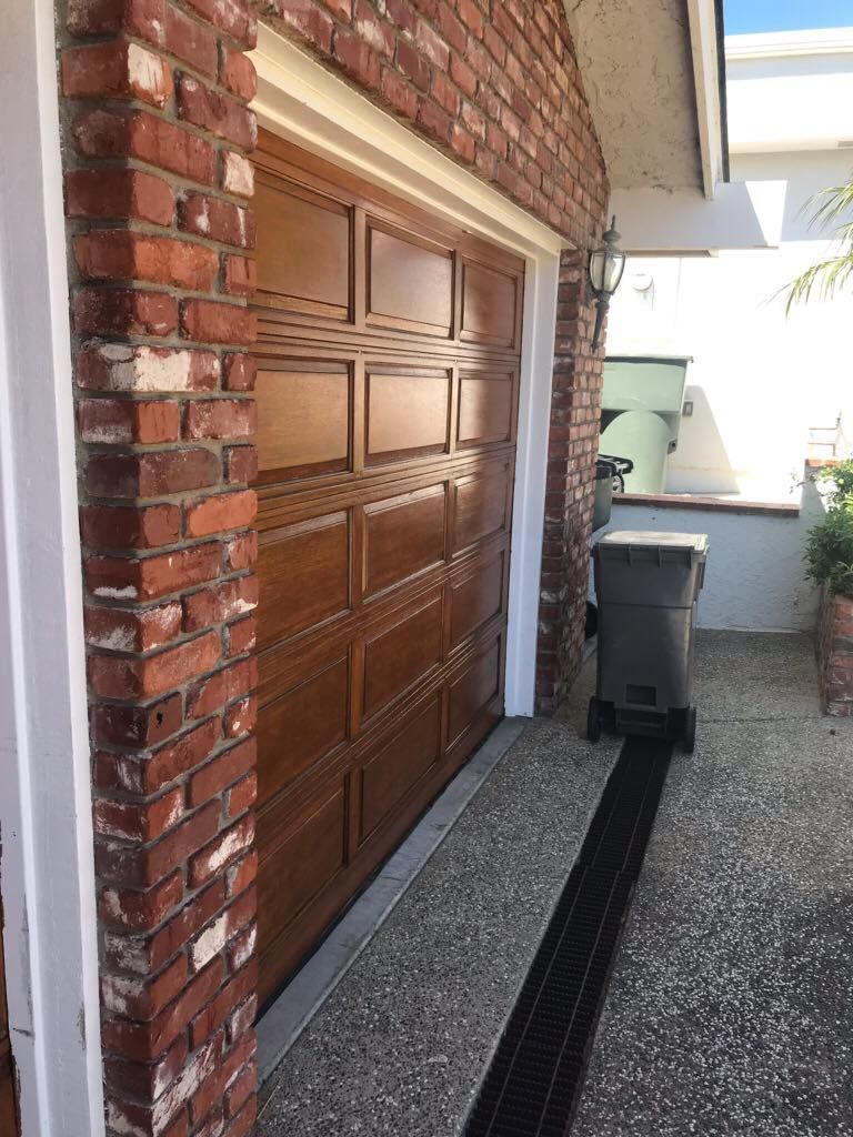 A wooden garage door is sitting next to a brick wall.
