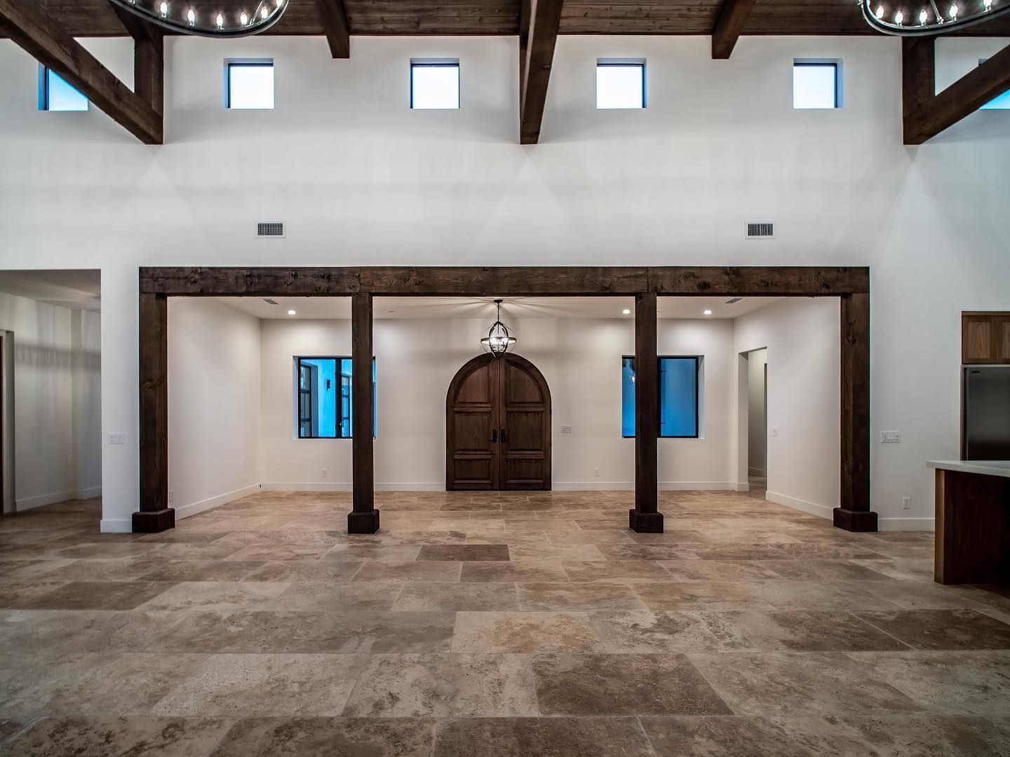 A large empty room with wooden beams and a wooden door.