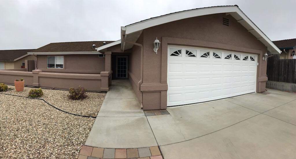 A house with a white garage door and a walkway leading to it.