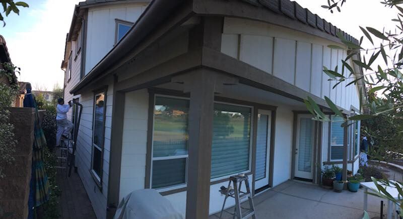 A man is painting the side of a house