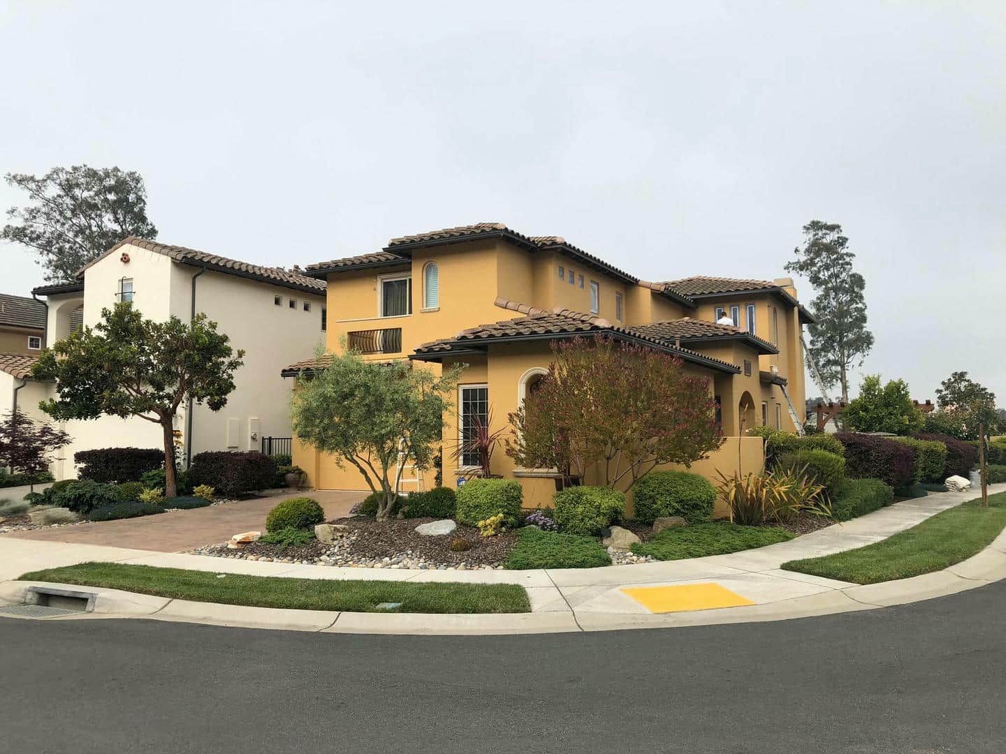A large yellow house is sitting on the corner of a street.