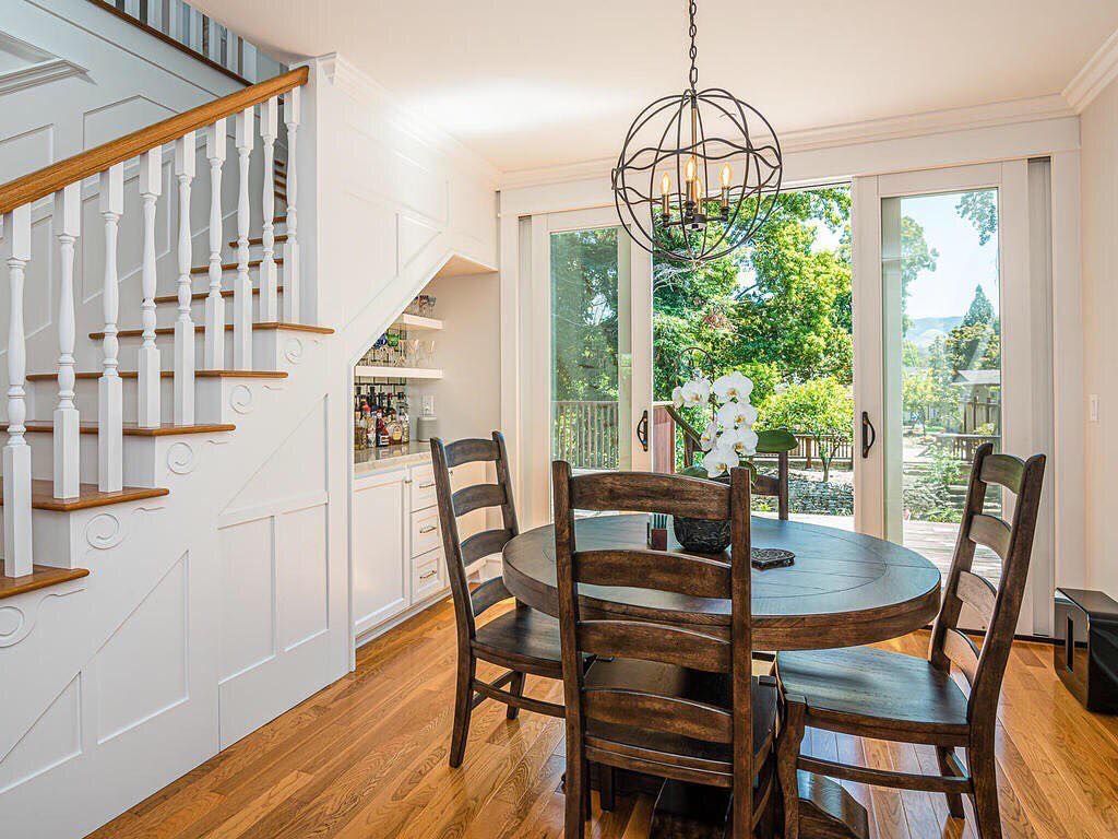 A dining room with a table and chairs and stairs leading up to the second floor.