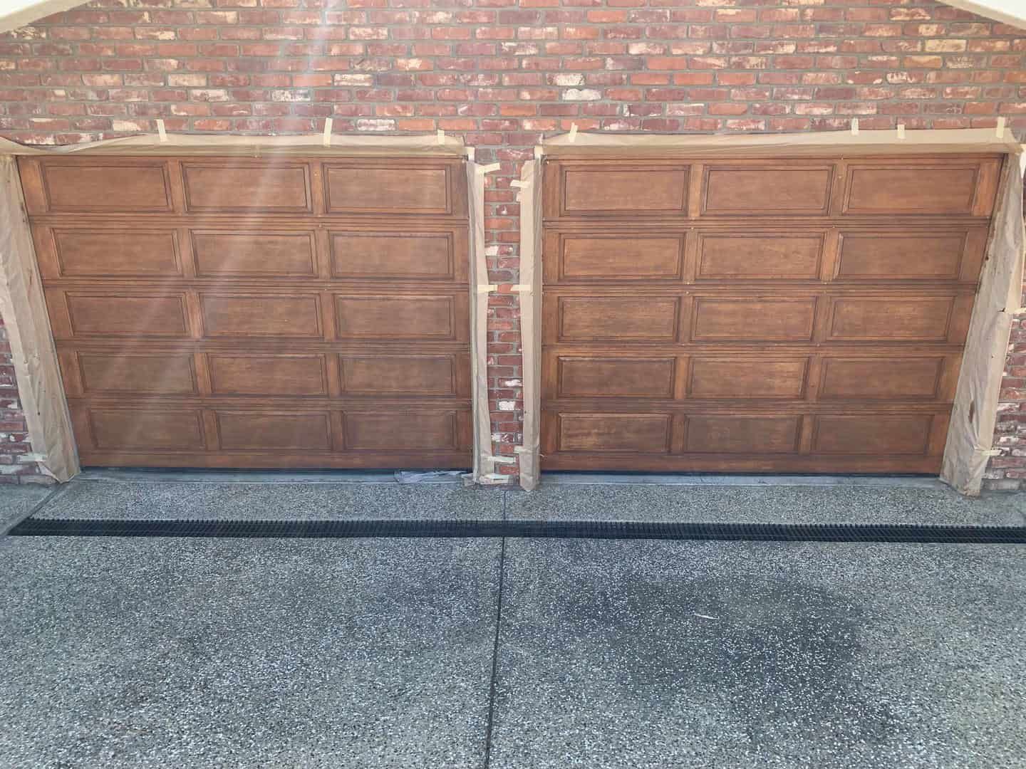 A pair of wooden garage doors on a brick building.