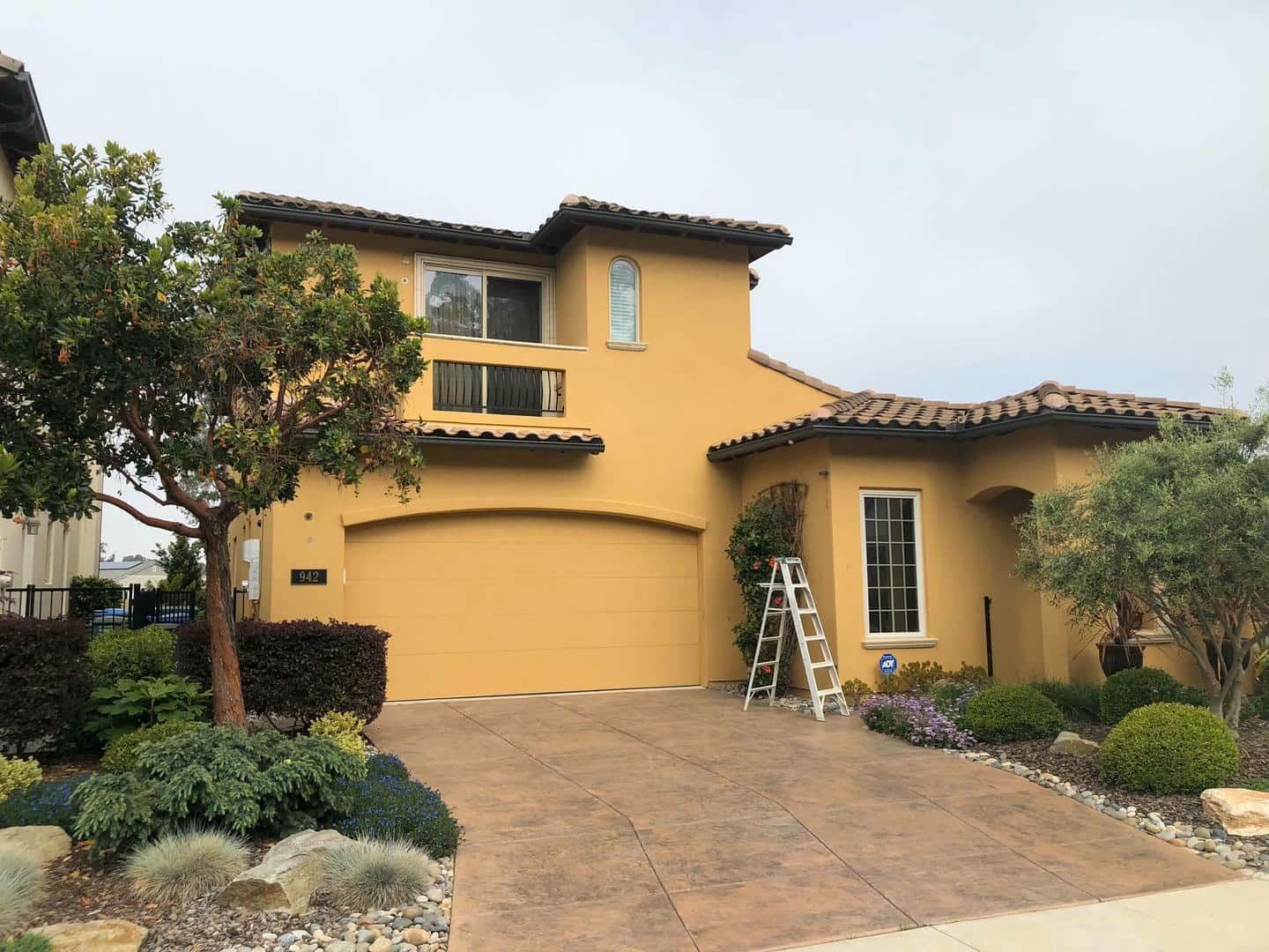 A large yellow house with a ladder in front of it.