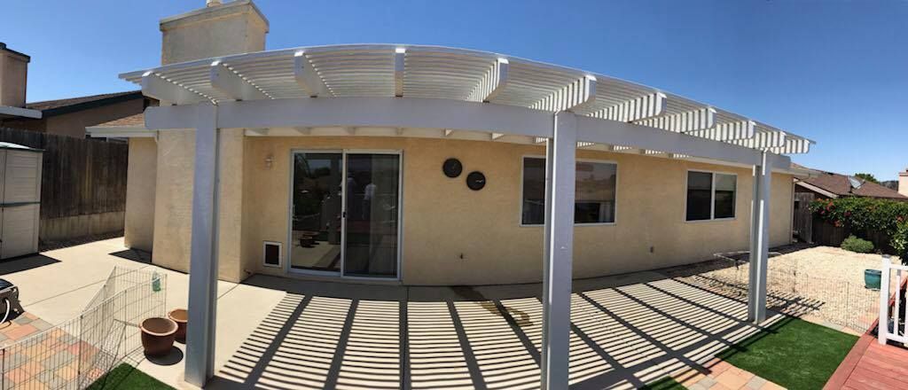 A house with a pergola and a patio in front of it.