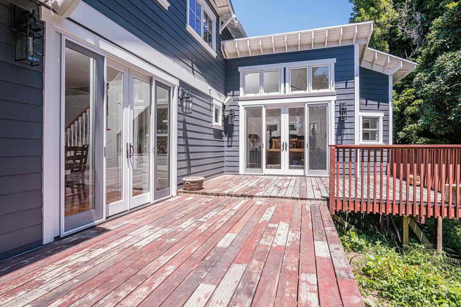 A large house with a large wooden deck and sliding glass doors.