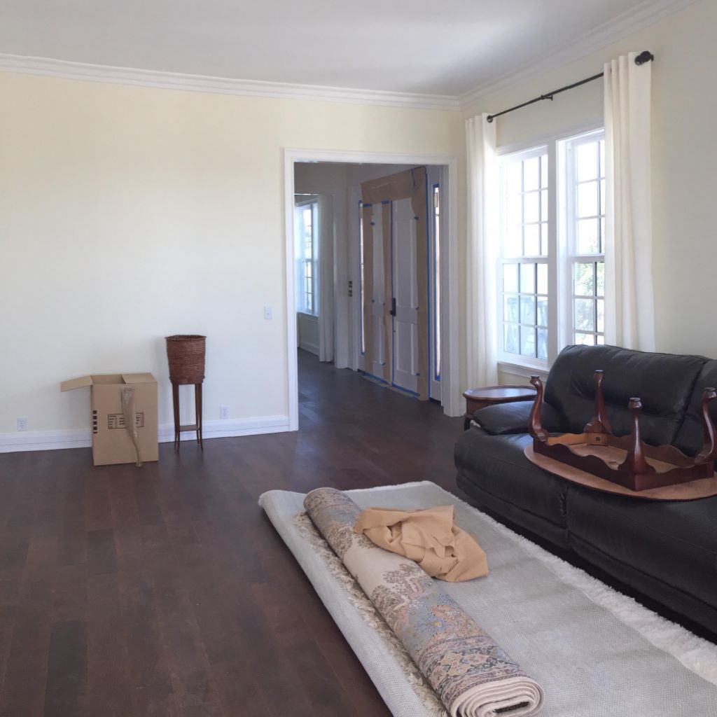 A living room with a black couch and a rug on the floor