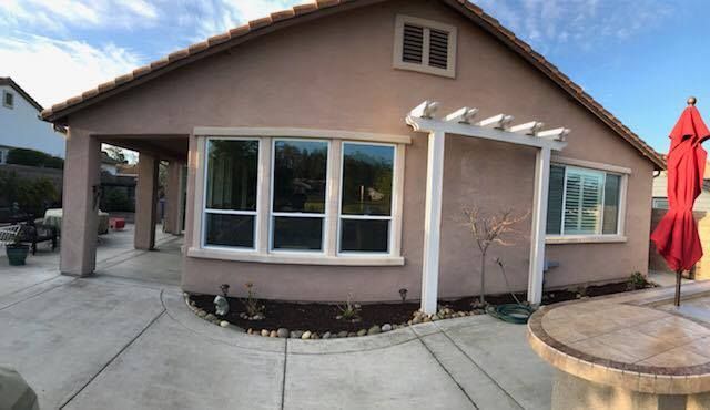 A house with a pergola and a red umbrella in front of it