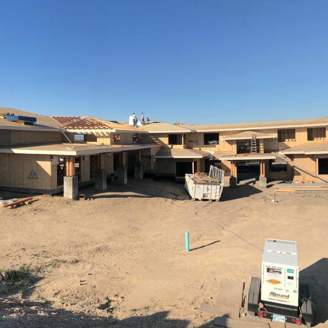 A large house is being built in a dirt field.