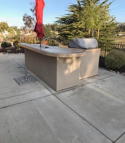 A patio with a grill and an umbrella on it