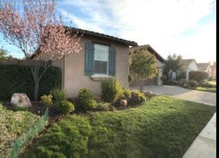A house with a lush green lawn and trees in front of it.