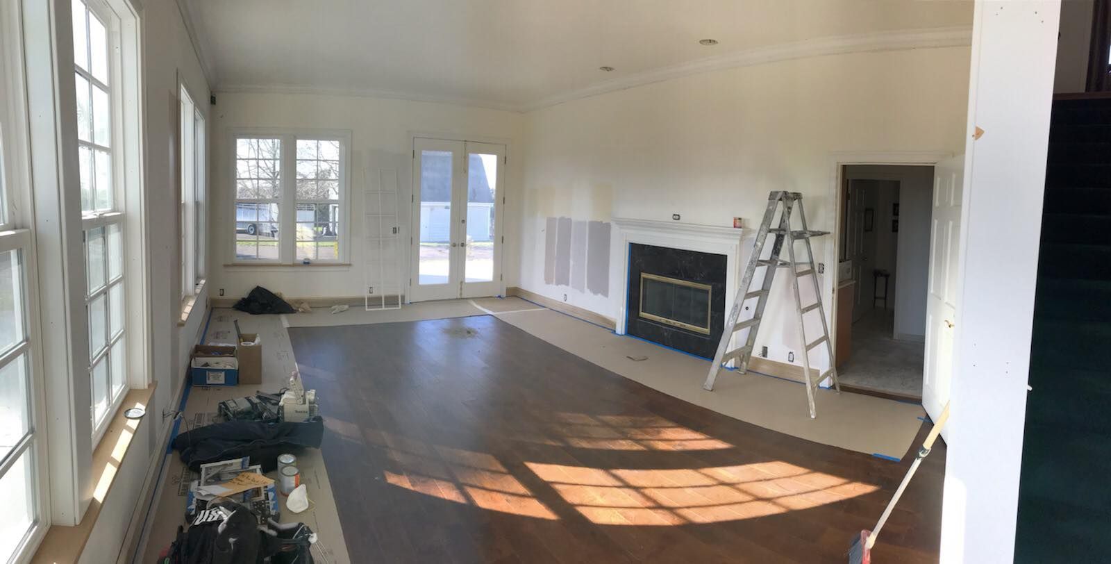 A large empty living room with a fireplace and a ladder.